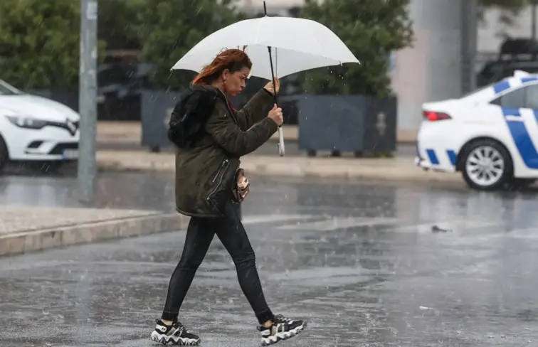 Senhora a atravessar a estrada alagada devido à chuva e mau tempo
